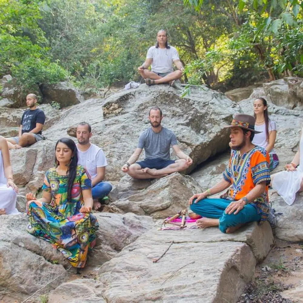 Grupo en meditación sobre las piedras del río
